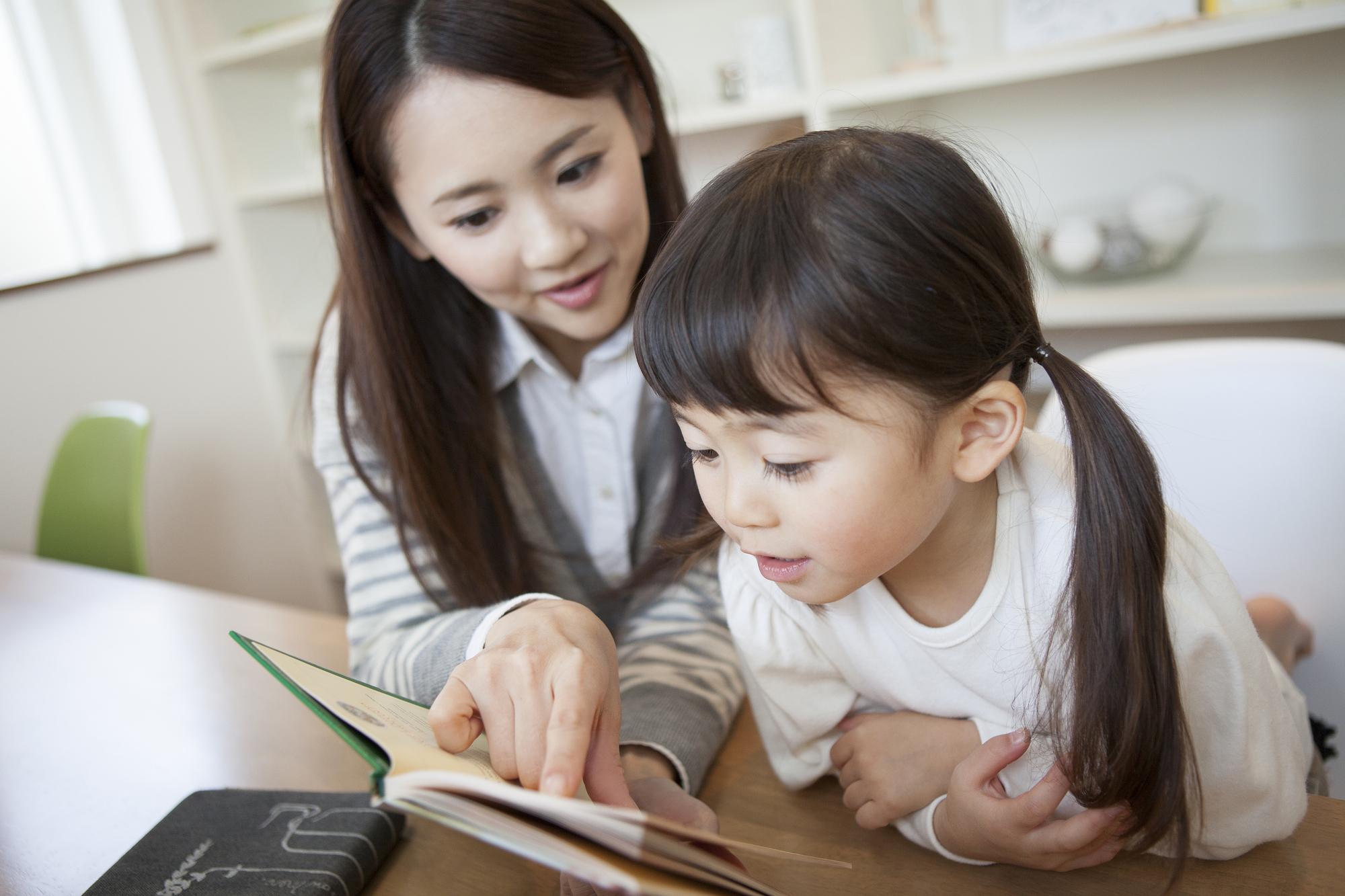 絵本を眺める女の子と母親