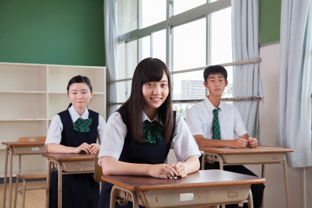 教室で着席している3人の高校生